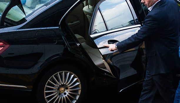 Luxury black limousine parked in central London near iconic landmarks.